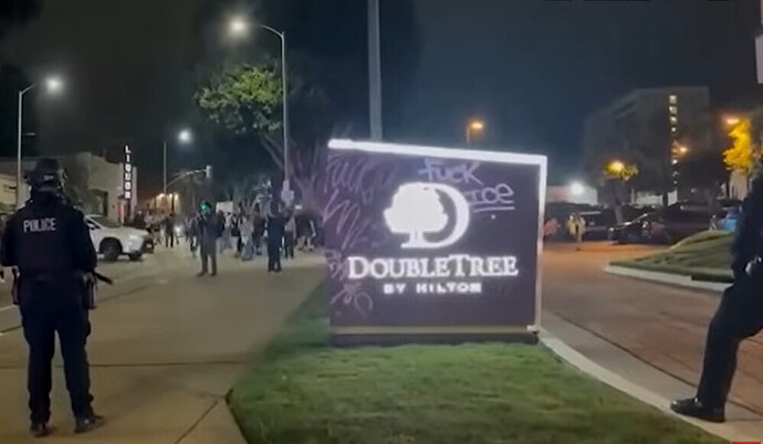 Riot police standing outside the Double Tree hotel in Los Angeles, protesters demanding ICE agents leave